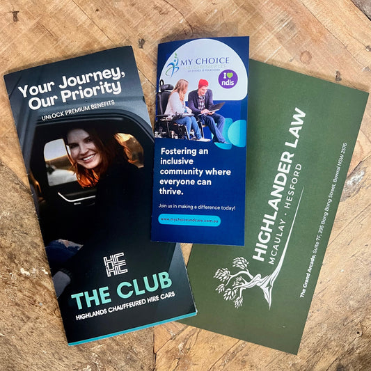 Three brochures from different companies on a wooden surface